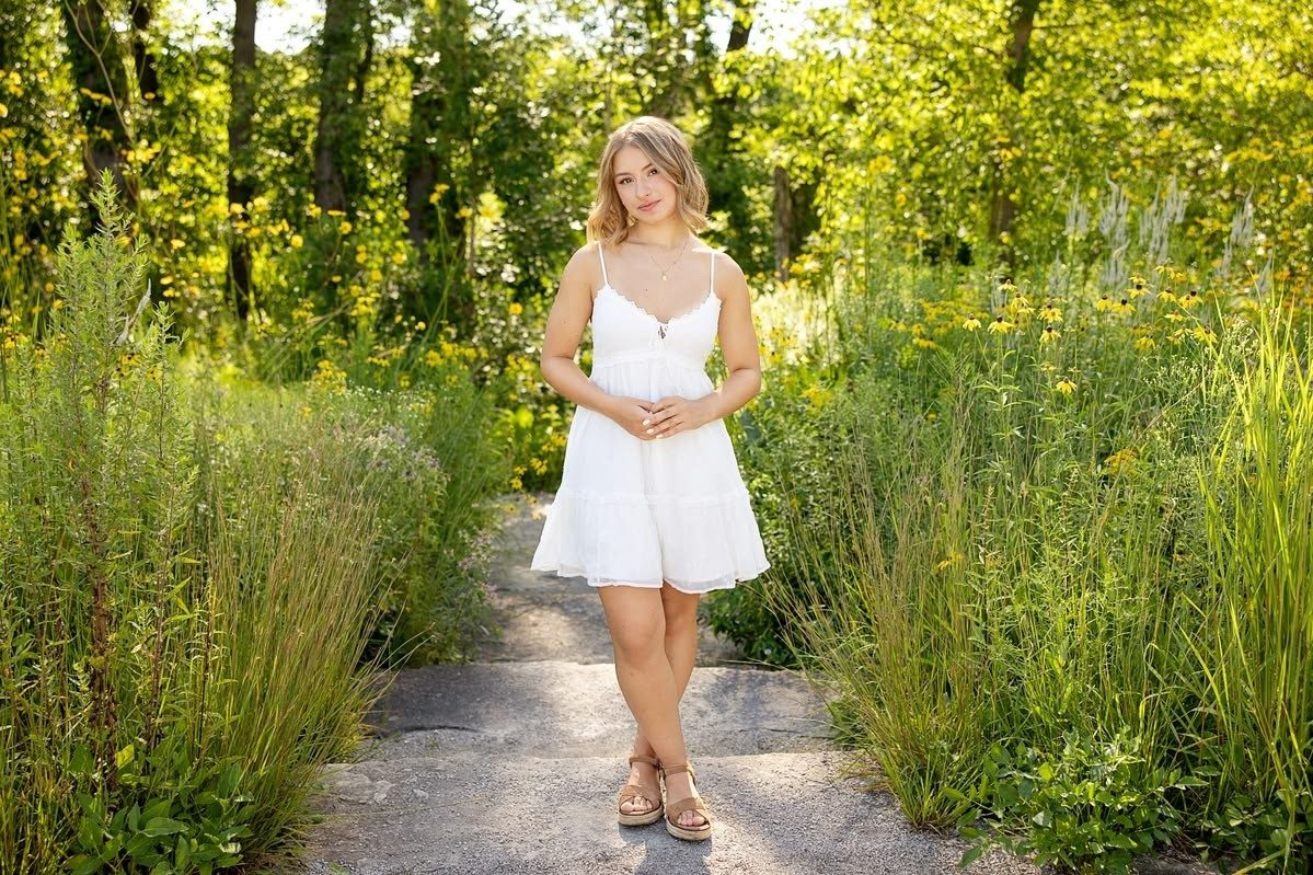 Madalina in een witte zomerjurk in een groene parksetting
