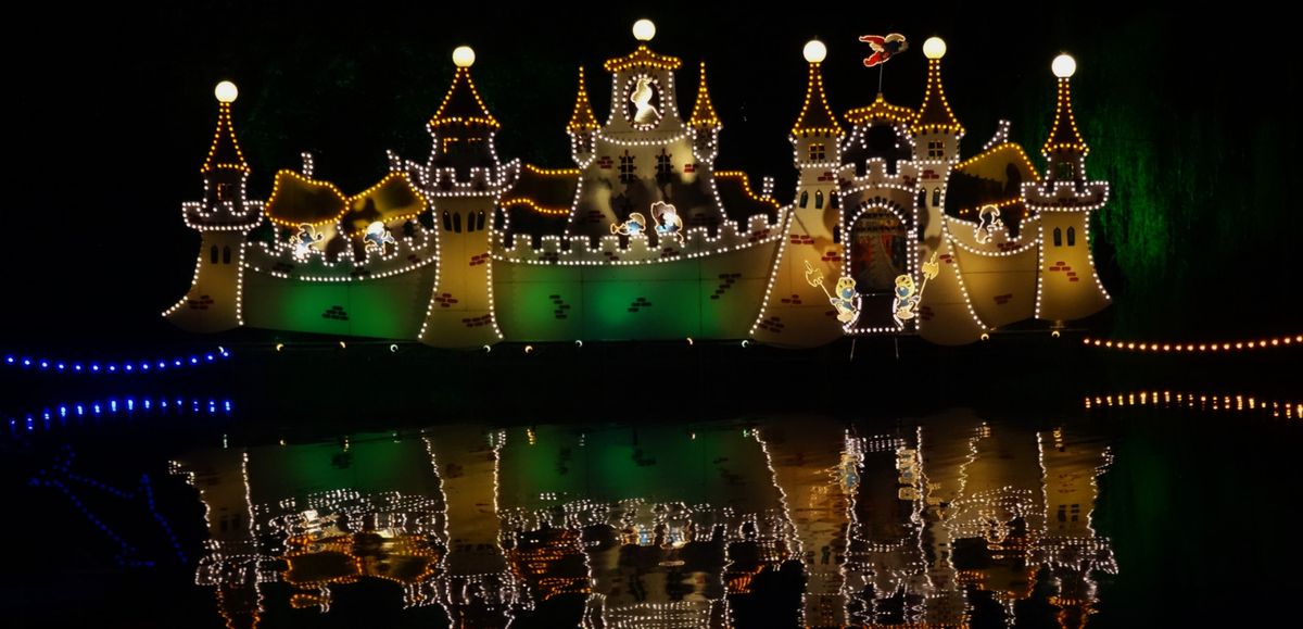 Illuminated Lichtjesroute display reflected in the water at night